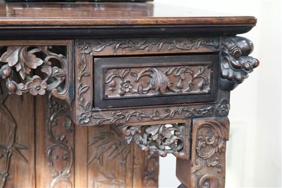 A late 19th century/early 20th century carved Chinese hardwood desk, carved in the round with bamboo flowers and foliage with possibly